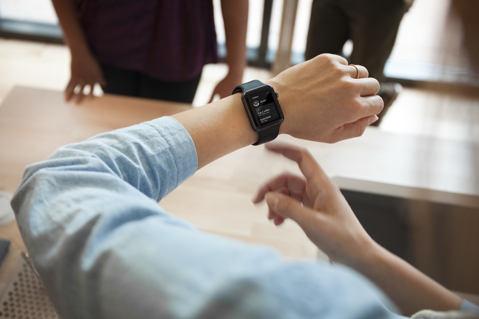 A customer receiving an order notification on their Apple Watch at the café counter